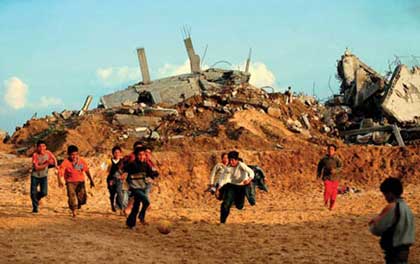 Palestinian children play football beside destroyed homes in the Gaza Strip