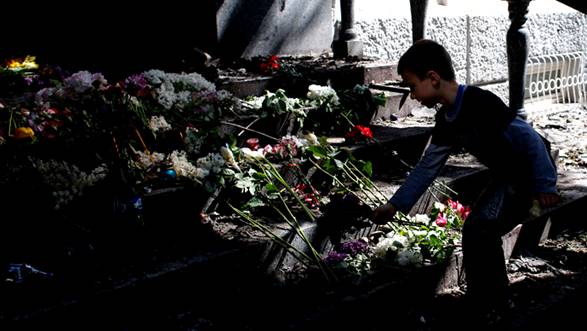 A boy places flowers in front of a gutted police station building in Mariupol, eastern Ukraine May 10, 2014.(Reuters / Marko Djurica)