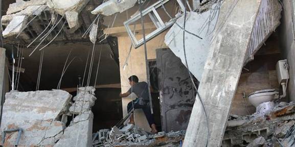 A member of the Palestinian Abu Lealla family examines the damage to his destroyed house following an Israeli airstrike north of Gaza City on, 11 July 2014.
