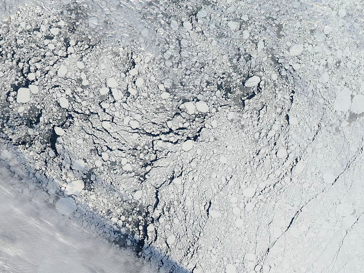 An image of an area of the Arctic sea ice pack well north of Alaska, captured by the MODIS instrument on NASA's Aqua satellite on Sept. 13, 2013. A cloud front can be seen in the lower left, and dark areas indicate regions of open water between sea ice formations. <i><b>Image Credit: Image courtesy NASA Worldview</b></i>