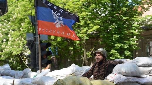 A member of the federalization supporters' self-defense movement is seen at the barricades near the flag of the Donetsk People's Republic (RIA Novosti/Mikhail Voskresenskiy)