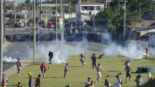 Demonstrators run during clashes with riot police near the Estadio Castelao in Fortaleza
